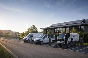 Elektrische Unternehmensfahrzeuge laden an Ladepunkten vor einem Gebäude mit Photovoltaikanlage